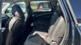 Rear passenger area of a black Acura SUV with the rear door open, showing black leather seats and center console area.