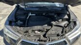 Front view of a car with the hood open, exposing the engine bay and various components like the battery and hoses.