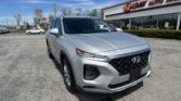 Silver Hyundai SUV in a dealership lot, in front of an EZ LOAN Auto Sales building on a sunny day