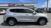 White SUV parked in a dealership lot with an EZ LOAN AUTO SALES sign on a white building against a blue sky.