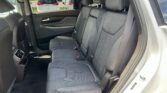 Back seat of a car with gray fabric seats, headrests, and seatbelts visible in a parked lot perspective through the window.