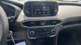 In‑car view of the dashboard with a touchscreen display showing AV Off and car icons, parked in a lot seen through the windshield