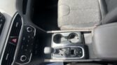 Front interior of a car: center console, gear shifter, cup holders, and passenger seat visible from a tilted angle.