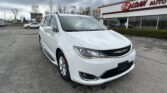 White minivan parked in the foreground outside an EZ Loan Auto building on a cloudy day in a dealership lot