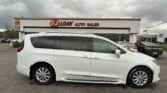 White minivan parked in a dealership lot with a building reading 'E-Z LOAN AUTO SALES' in the background under a cloudy sky.