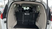 Open rear of a white SUV with the tailgate up, showing two rows of black seats and cargo space in the back region.