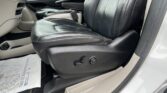 Front interior of a car showing a black leather passenger seat, center console, and beige door panel.