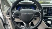Driver’s view of a car steering wheel with a Chrysler emblem and illuminated blue instrument cluster behind it