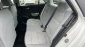 Back seat of a gray fabric car interior with three-seat belt and door panel visible, parked in a lot outside the window.