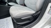 Interior of a car showing the front seats, center console with a manual gear shifter, and a door frame with a warning sticker visible on the frame. The seats are light gray and lightly stained.