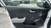 View from inside a white car with the front passenger door open, overlooking a car dealership lot with many parked vehicles across the pavement.