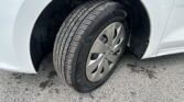 Close-up of a car tire and alloy wheel in the wheel well, on a light-colored car side panel.