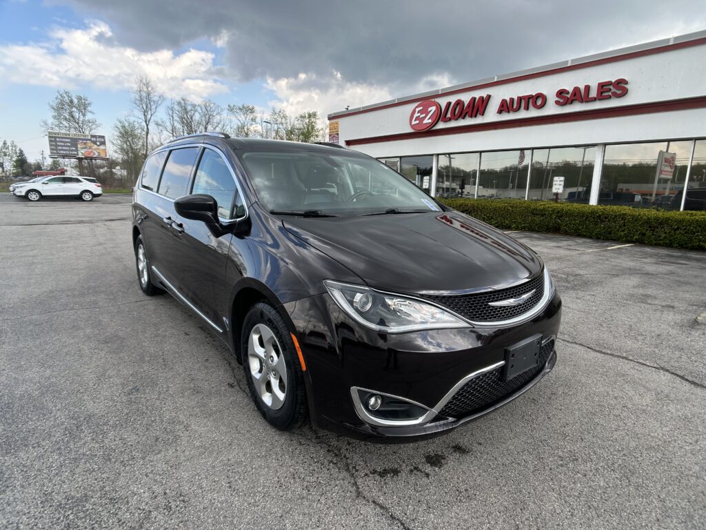 Dark gray minivan parked in front of an E-Z Loan Auto Sales showroom.