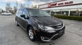 Dark gray minivan parked in front of an E-Z Loan Auto Sales showroom.