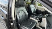 Interior of a car with black leather seats and orange stitching, driver and front passenger seats visible, door open.