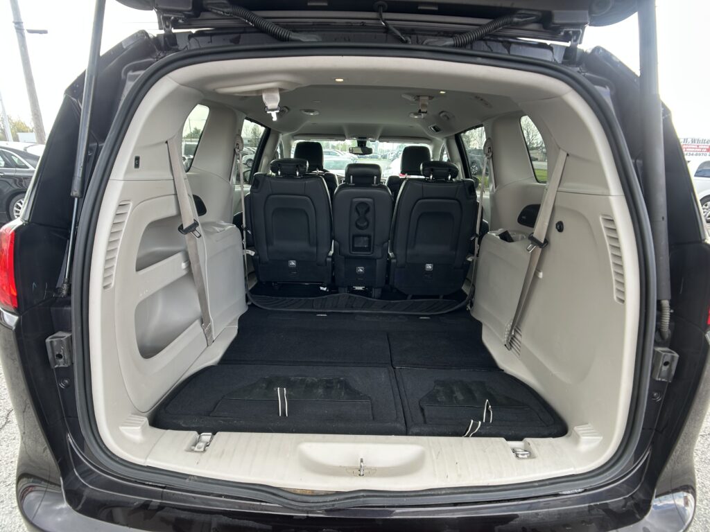 Open rear hatch showing cargo area with third-row seats upright in an SUV/minivan interior.