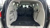 Open rear hatch showing cargo area with third-row seats upright in an SUV/minivan interior.