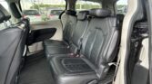 Black leather three-row vehicle interior with captain chairs and rear seating, visible parking lot outside through the windows