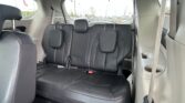Interior of a gray SUV showing black leather rear seats with headrests and a parking-lot view through the windows. The second row is upright with visible seat belts.