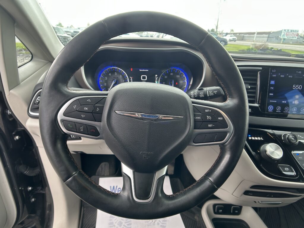 Steering wheel close-up with digital instrument cluster and infotainment screen in a car interior.