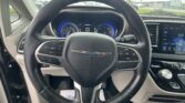 Steering wheel close-up with digital instrument cluster and infotainment screen in a car interior.
