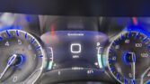 Close-up of a car instrument cluster showing the speedometer at 0 mph, tachometer, and digital readouts with blue lighting