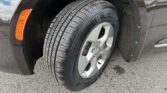 Tire and alloy wheel on a dark car, close-up view showing tread pattern and wheel rim with orange side marker nearby.