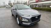Gray Hyundai SUV in a rainy parking lot in front of an EZ Loan Auto dealership building with large glass windows and red signage.