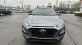 Front view of a gray Hyundai SUV with a roof rack, parked in a rainy dealership lot.