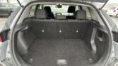 Open SUV hatchback showing empty cargo area with rear seats up and dark carpeting, side pockets, and cargo hooks visible at floor edges