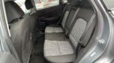 Rear seating area of a compact SUV with black and gray checkered upholstery, showing three seats and visible seat belts in the back row.