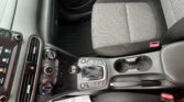 Front car passenger seat and center console with gear shifter, cup holders, and dashboard controls visible inside a compact SUV/ sedan edge-to-edge view.