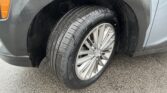 Close-up of a car's front left wheel with the gray fender and orange side marker nearby.