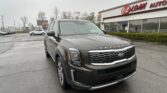 Front-right view of a gray Kia Telluride SUV parked in a car lot with an EZ Loan Auto dealership building in the background.