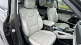Front interior of a car showing light gray leather seats, center console, and dashboard area.