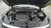 Open car hood revealing engine bay of a Kia SUV in a parking lot area