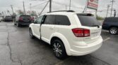 White SUV parked at a car dealership lot with other vehicles and an EZ LOAN sign in the background.