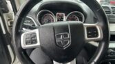 Interior view of a car focusing on the steering wheel with Dodge emblem and dashboard gauges in the background, parked in a lot.
