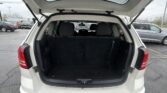 Open tailgate of a white SUV in a parking lot, showing folded rear seats and cargo area