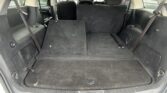 Cargo area of an SUV with the rear seats folded, showing black carpet and side panels in the trunk.