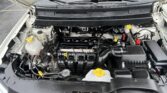 Car hood open, showing the engine bay with coolant reservoir (yellow cap), battery, hoses, and air intake components visible beneath the windshield.