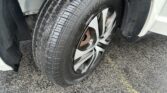 Close-up of a car tire and alloy wheel mounted on a vehicle, with the wheel well and fender visible.