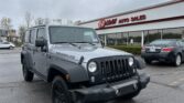 Gray Jeep Wrangler parked in front of E-Z Loan Auto Sales storefront in a dealership lot on a cloudy day.