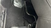Under-seat view of car interior showing a metal seat track/bracket and loose wiring near the front seat cushion.