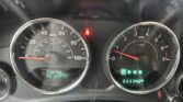 Vehicle dashboard with speedometer and tachometer, central red seatbelt warning, and a digital readout showing miles to empty. The PRND gear indicator is illuminated.