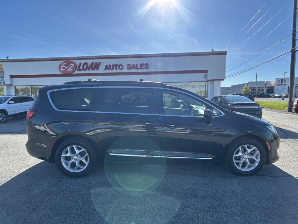 Black SUV in the foreground at an EZ LOAN Auto Sales lot, with the white dealership building and sign behind it on a sunny day