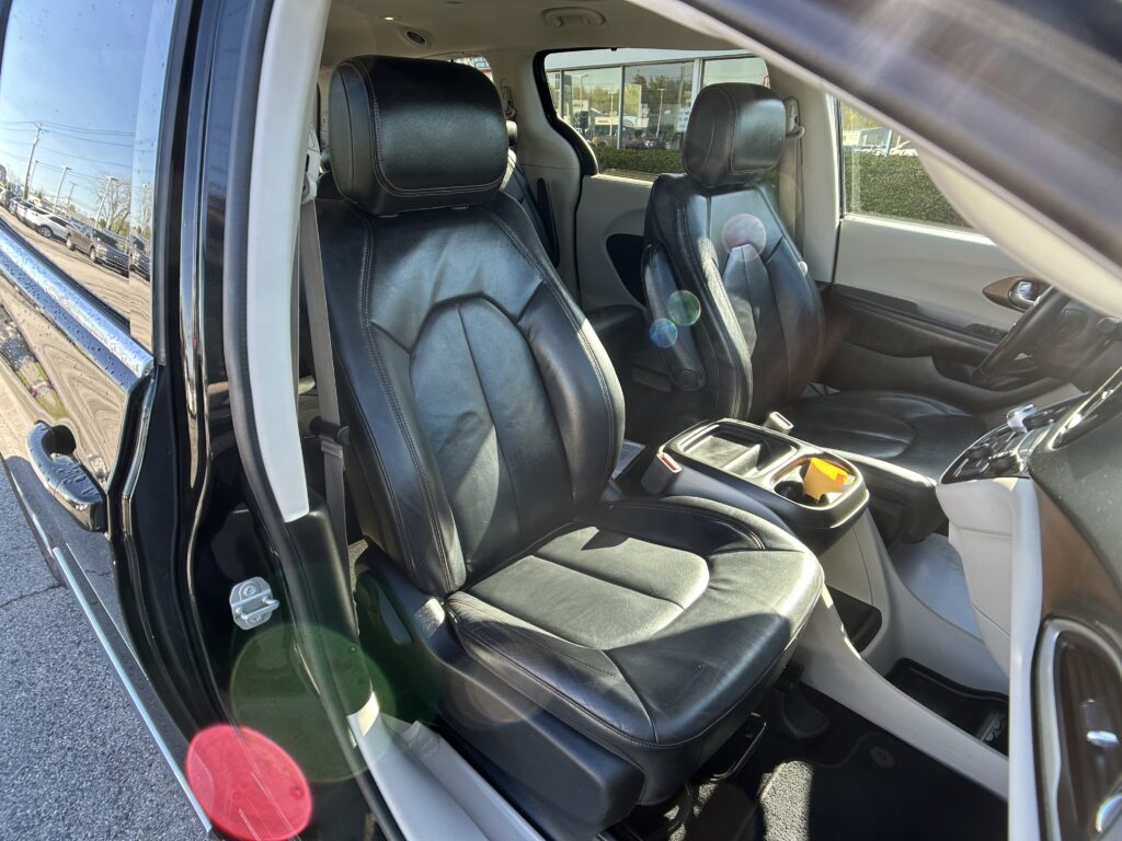 Inside a black leather SUV showing front and rear seats with the door open and parking lot outside the window.