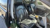 Inside a black leather SUV showing front and rear seats with the door open and parking lot outside the window.