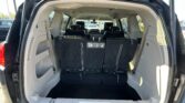 Open SUV hatch showing third-row seats upright and cargo area behind them, with headrests visible and silver latches/straps hanging from seats