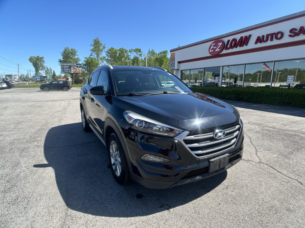 Black Hyundai SUV in a dealership lot, with an E-Z Loan Auto storefront in the background under a clear blue sky.